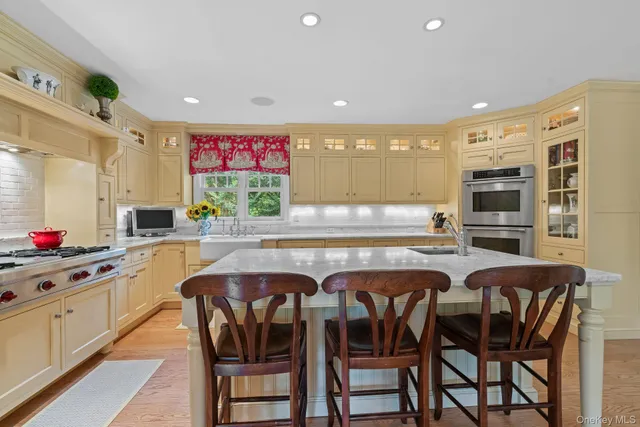 a kitchen with granite countertop lots of wooden cabinets stainless steel appliances a dining table and chairs