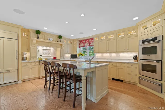 a kitchen with stainless steel appliances kitchen island granite countertop a table chairs sink and cabinets