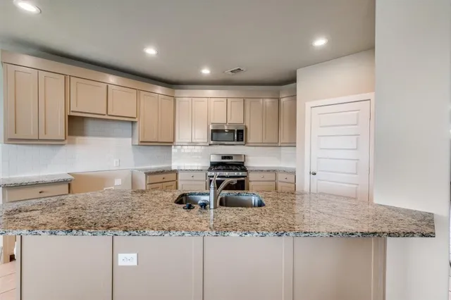 a kitchen with granite countertop a sink a stove and cabinets