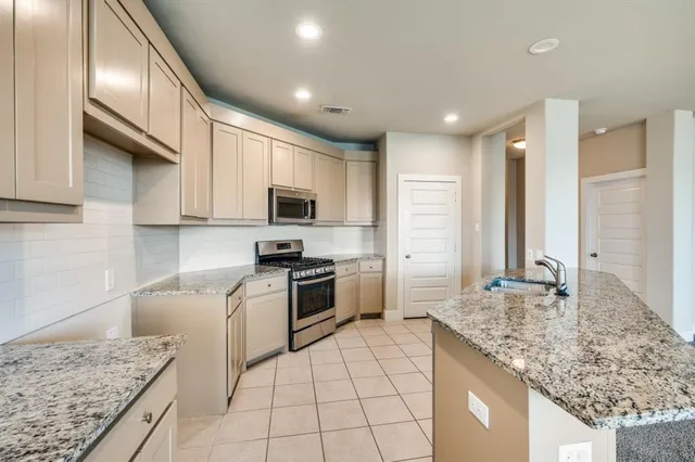 a kitchen with kitchen island granite countertop a sink stove and refrigerator