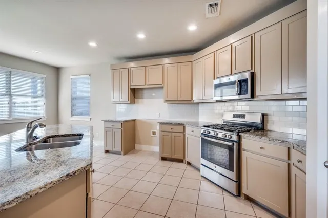 a kitchen with granite countertop a stove sink and cabinets
