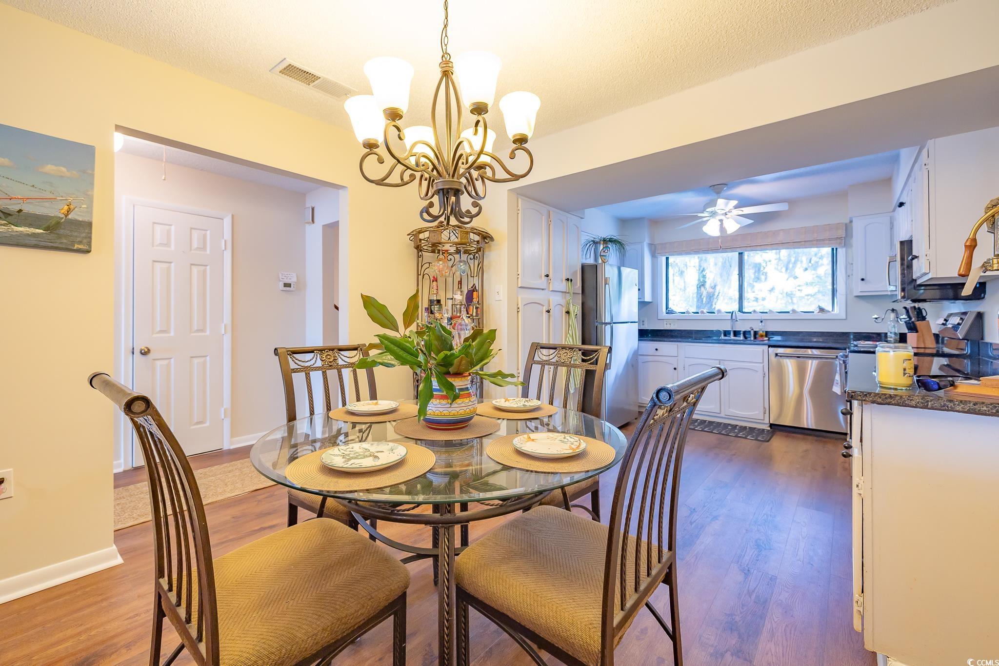 117 Finch Drive, Unit 272 Georgetown, SC 29440 - Photo 26 of 36 Dining area featuring dark wood-style flooring, a chandelier, ceiling fan, and a textured ceiling