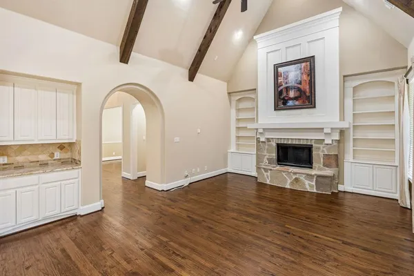 an empty room with wooden floor cabinet and windows