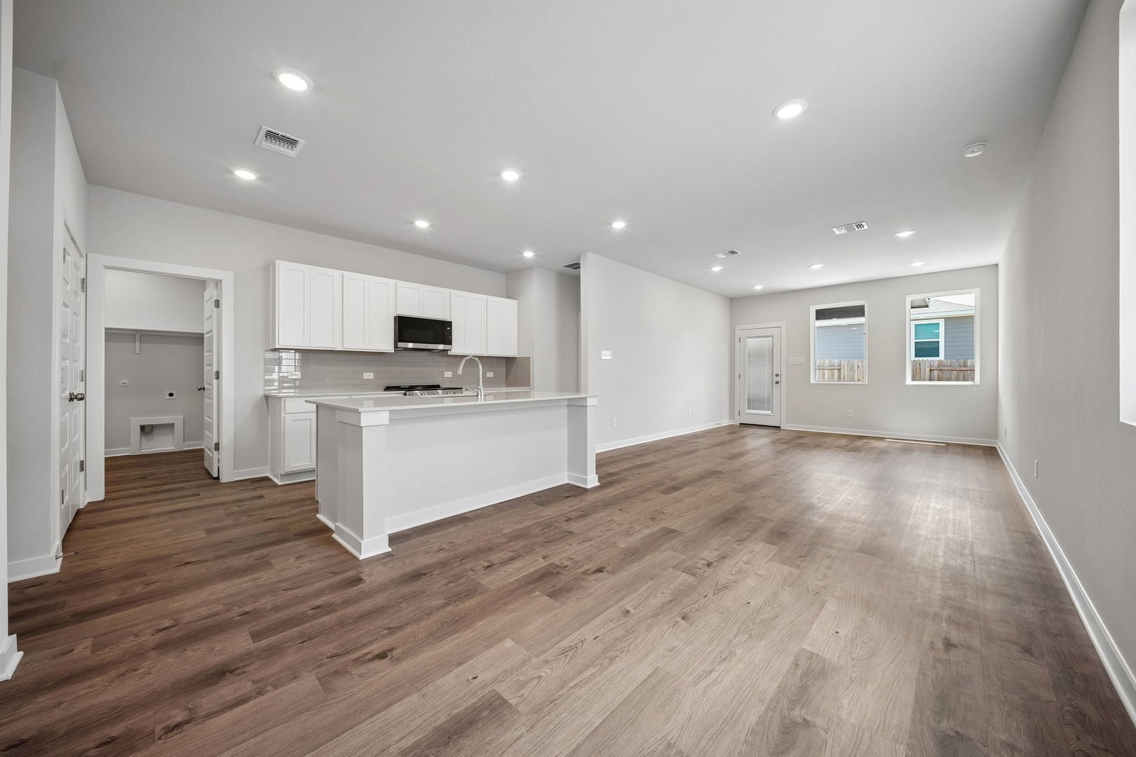 145 Hornet Street Elgin, TX 78621 - Photo 12 of 18 An open-concept layout unites the kitchen and living areas, highlighted by modern fixtures and seamless flooring.