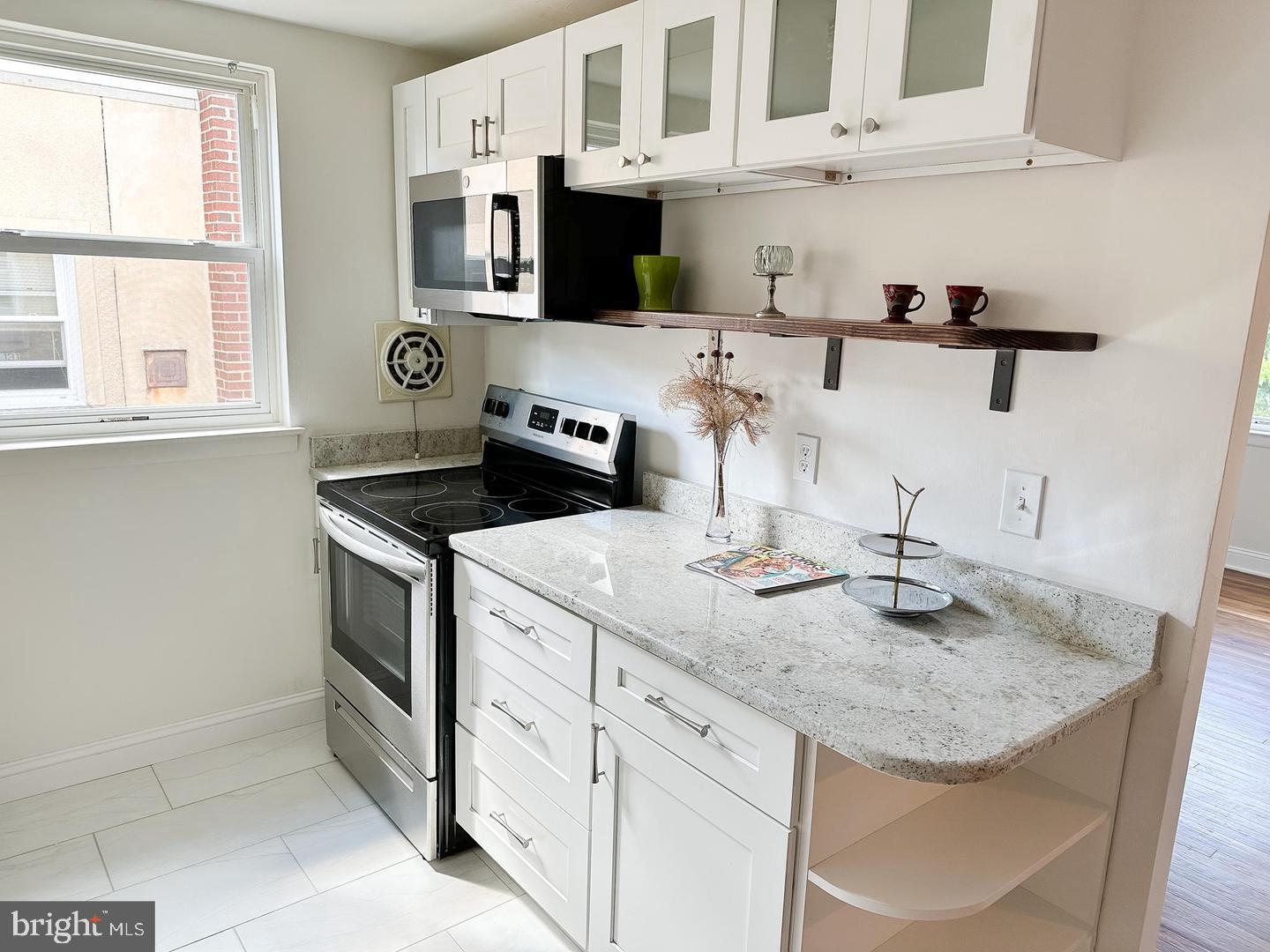 104 Clement Road, Unit D Oreland, PA 19075 - Photo 2 of 9 a kitchen with stainless steel appliances granite countertop a sink stove and cabinets