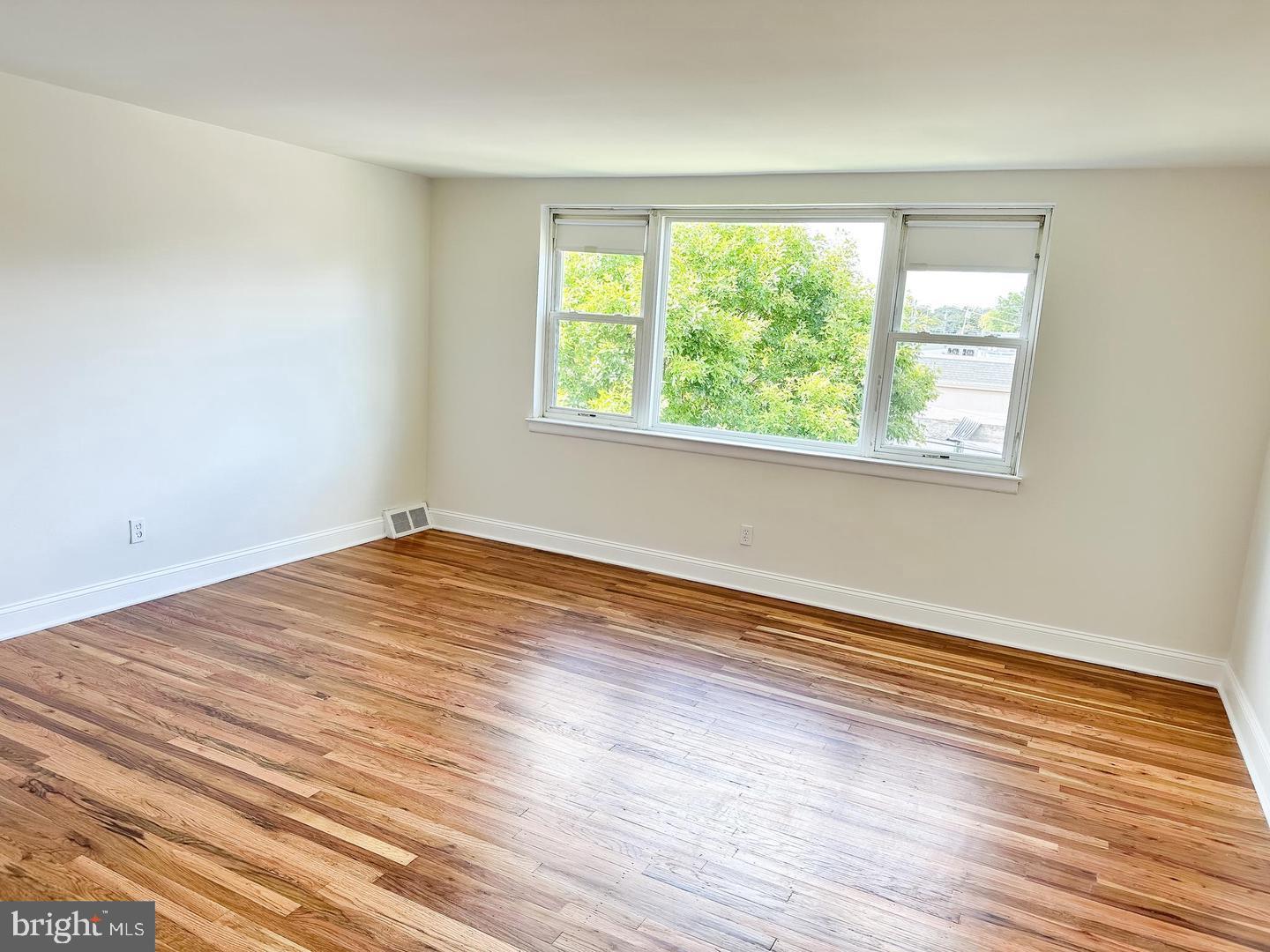 104 Clement Road, Unit D Oreland, PA 19075 - Photo 4 of 9 an empty room with wooden floor and windows