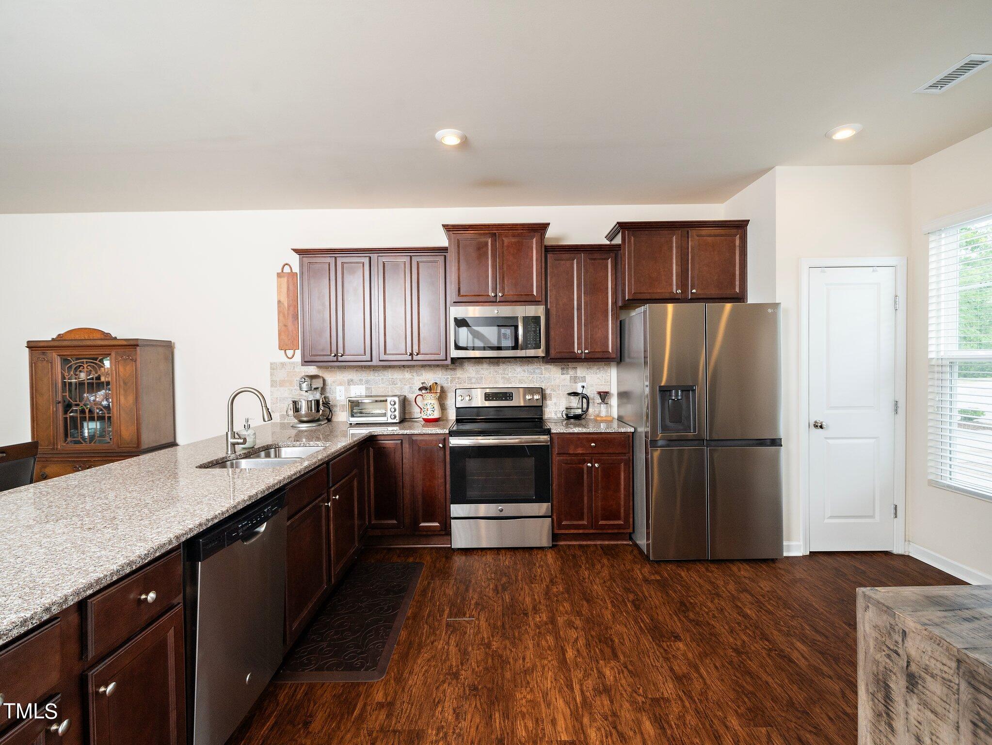 8804 Commons Townes Drive Raleigh, NC 27616 - Photo 4 of 21 a kitchen with stainless steel appliances granite countertop a refrigerator a sink dishwasher a stove with wooden cabinets and a granite counter top