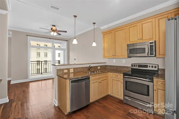 an empty room with wooden floor chandelier fan and windows