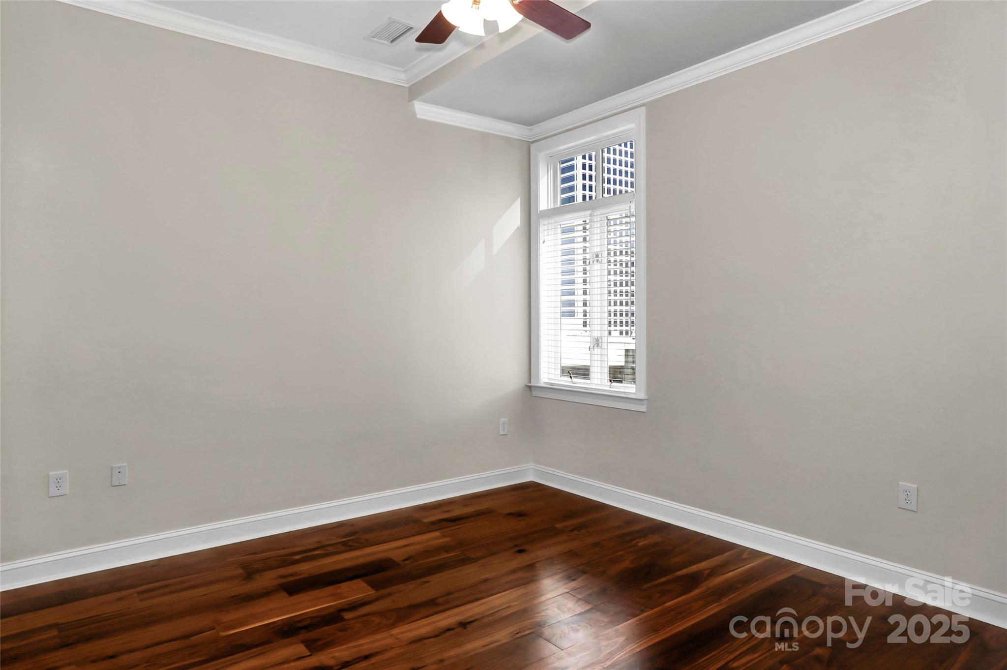 230 South Tryon Street, Unit 603 Charlotte, NC 28281 - Photo 24 of 32 an empty room with wooden floor chandelier fan and windows