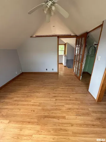an empty room with wooden floor chandelier fan and windows