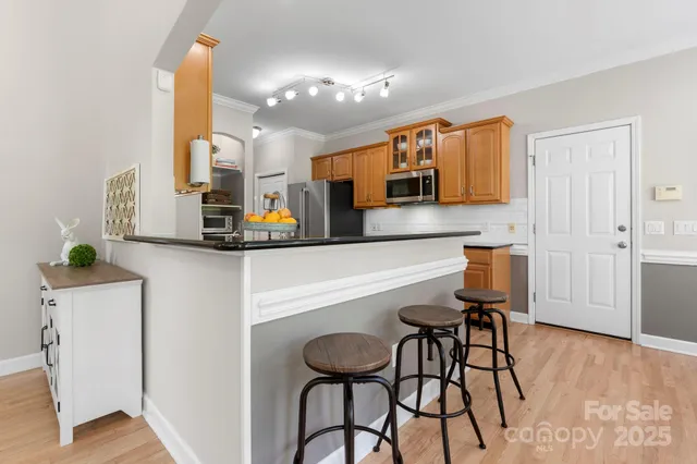 a kitchen with stainless steel appliances kitchen island granite countertop a table chairs and a refrigerator