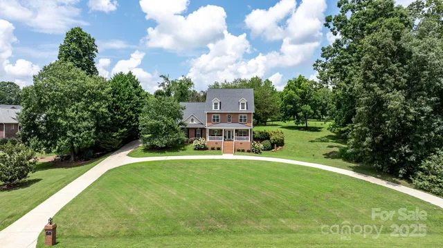 a view of a big house with a big yard plants and large trees