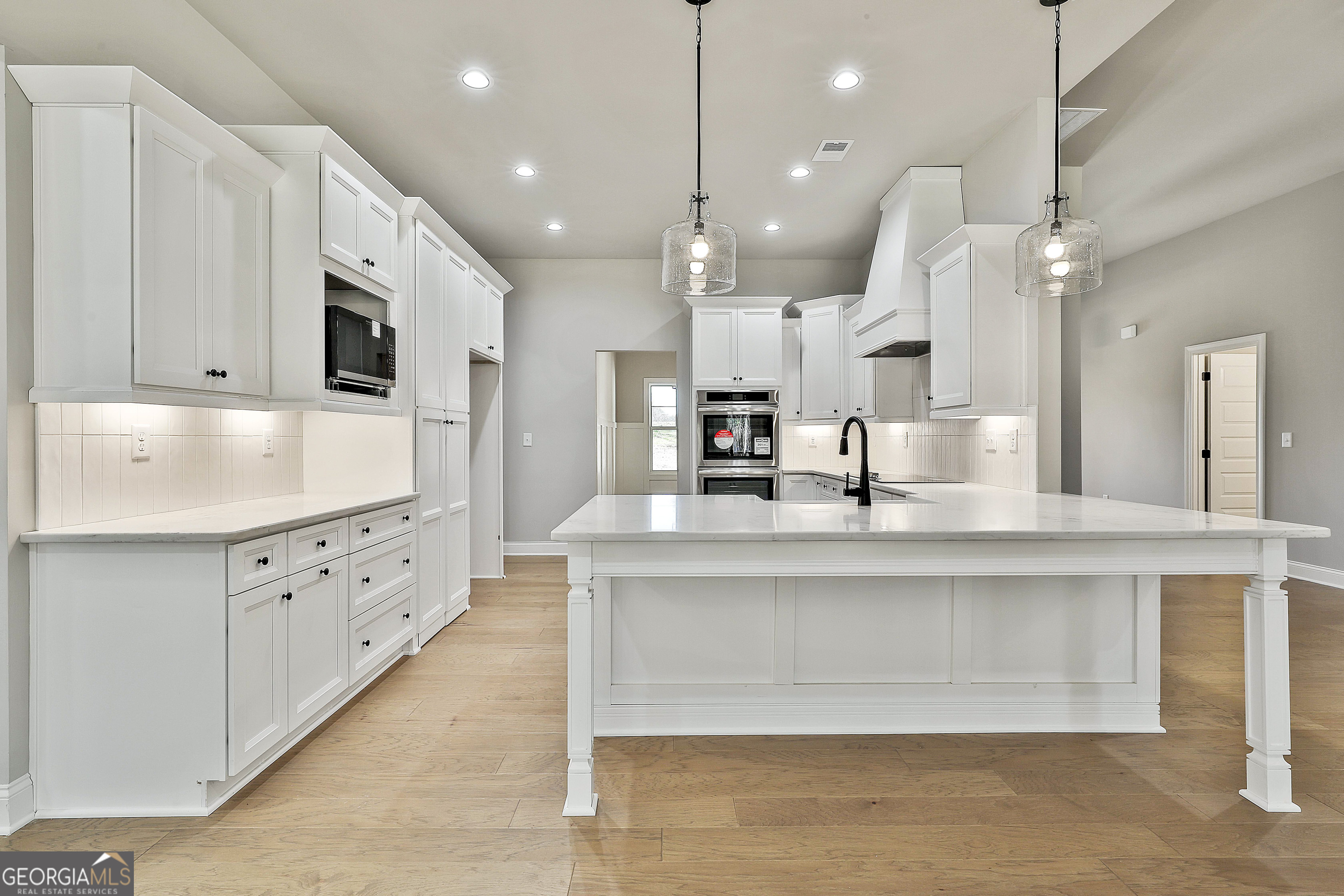 757 Alex Stephens Road Moreland, GA 30259 - Photo 25 of 45 a large white kitchen with lots of counter space wooden floor and stainless steel appliances