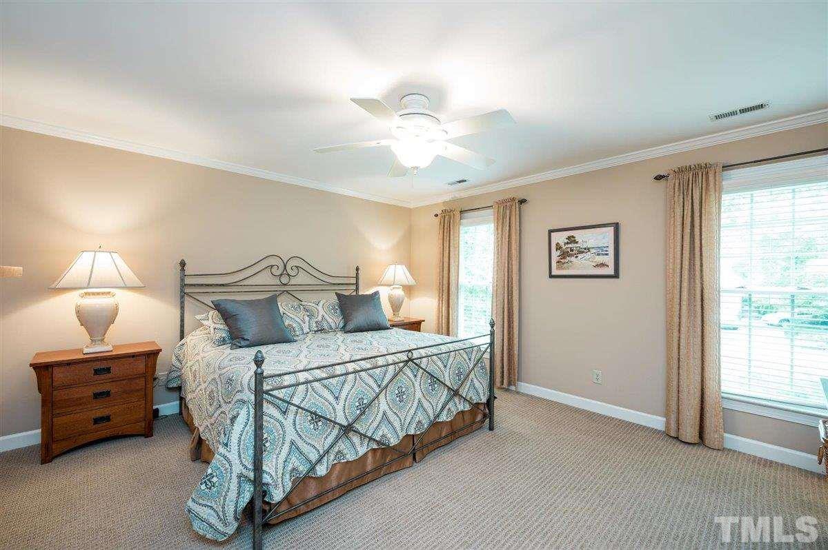 7916 Sutterton Court Raleigh, NC 27615 - Photo 13 of 25 a bedroom with a bed a chandelier and a window