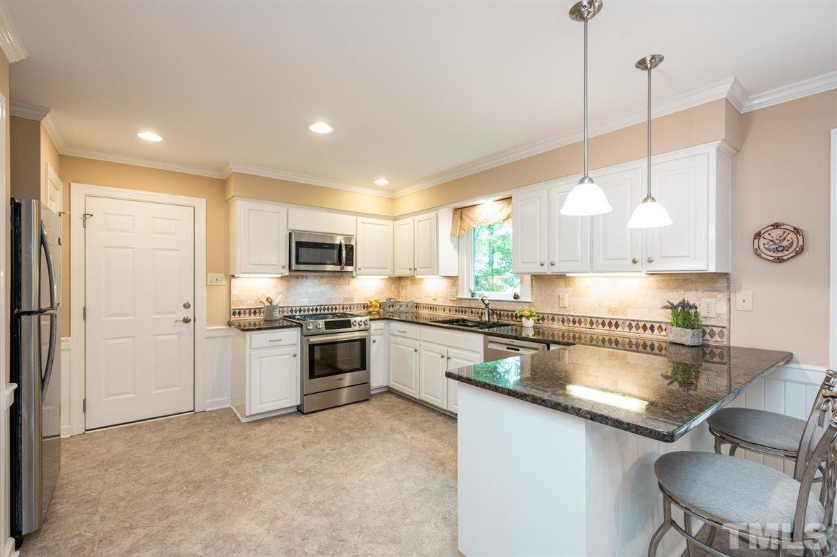 7916 Sutterton Court Raleigh, NC 27615 - Photo 7 of 25 a kitchen with stainless steel appliances granite countertop a sink a stove a refrigerator a center island with wooden cabinets and floor