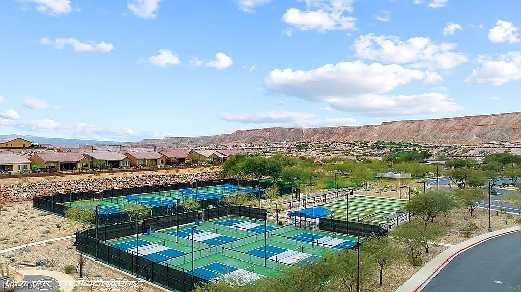 1304 Cottage Ridge Mesquite, NV 89034 - Photo 52 of 52 Numerous sport courts nestle amidst verdant landscaping, set against a distant mountain range and a residential neighborhood.