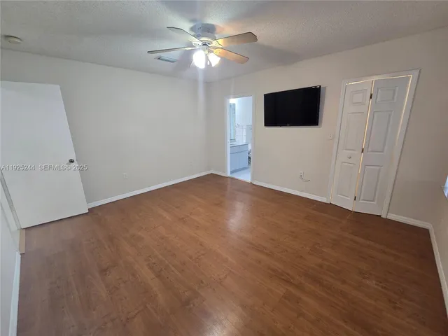 a view of a room with wooden floor and a ceiling fan