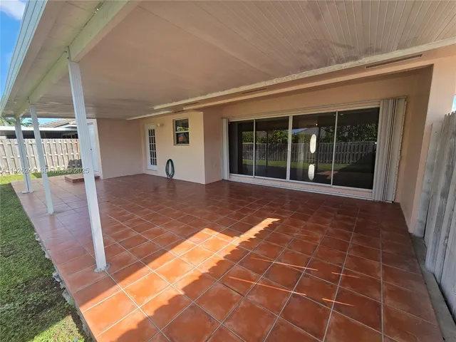an empty room with a chandelier fan and windows