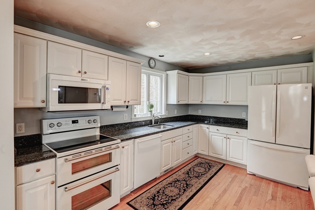 97 Weldon Farm Road Rowley, MA 01969 - Photo 8 of 37 a kitchen with granite countertop a sink stainless steel appliances and white cabinets