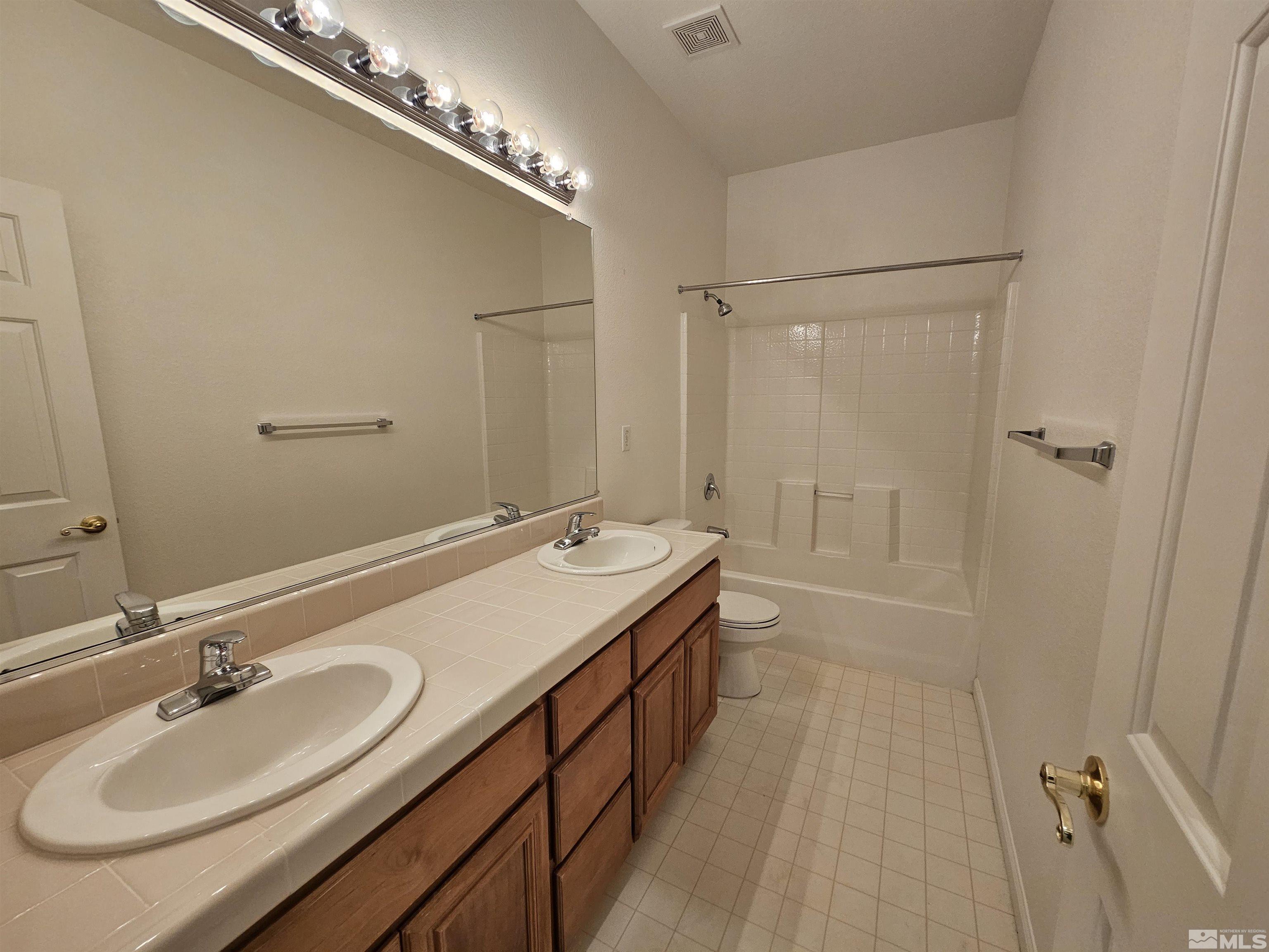 10575 Moss Wood Court Reno, NV 89521 - Photo 27 of 40 a bathroom with a double vanity sink a mirror and a shower