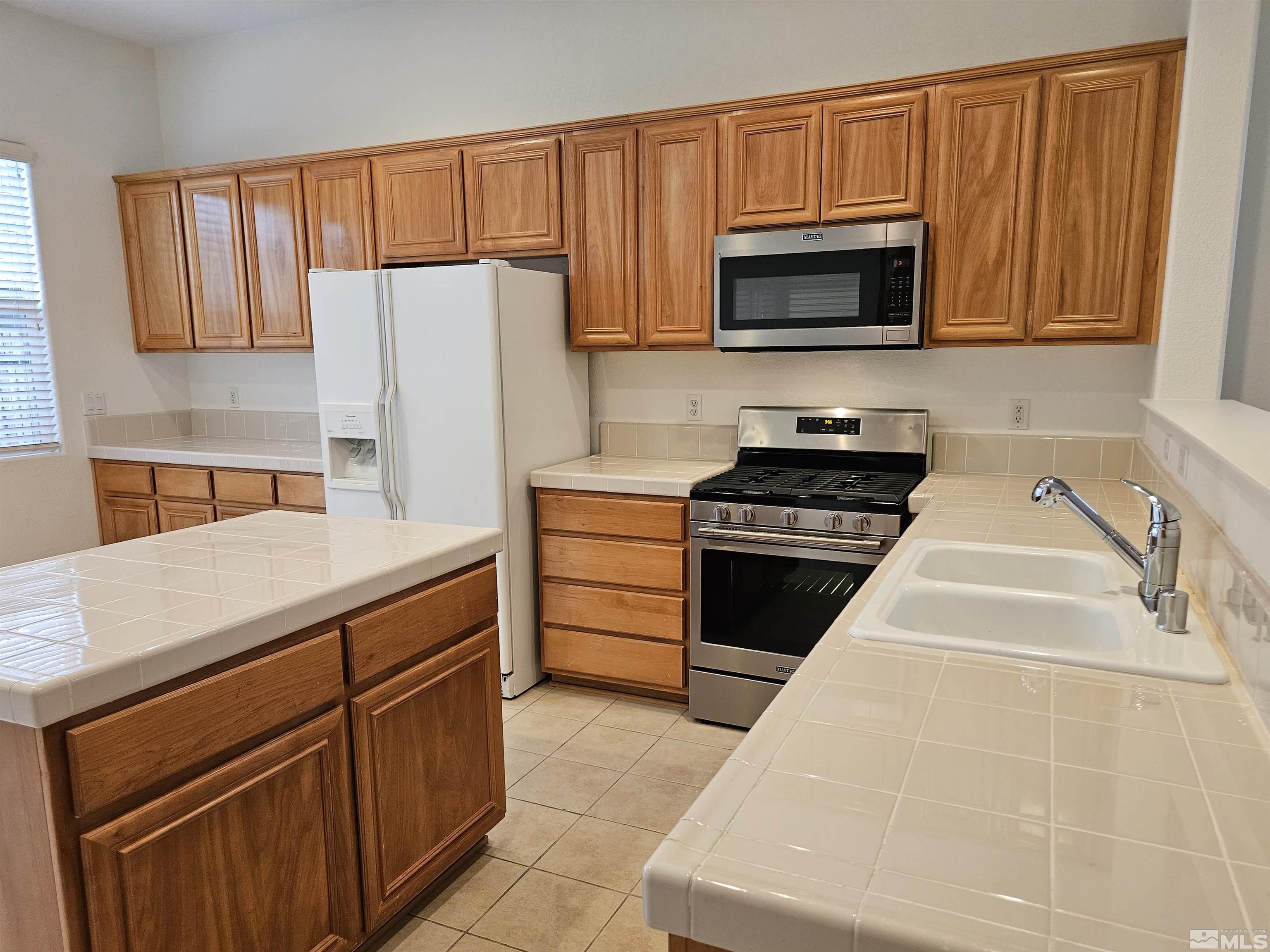 10575 Moss Wood Court Reno, NV 89521 - Photo 8 of 40 a kitchen with stainless steel appliances granite countertop a stove a sink and a microwave