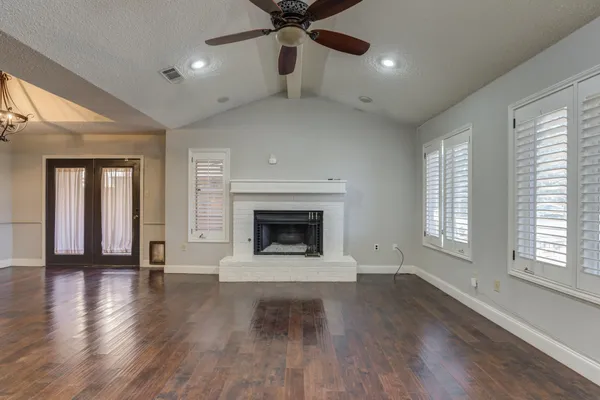 an empty room with wooden floor a fireplace and windows