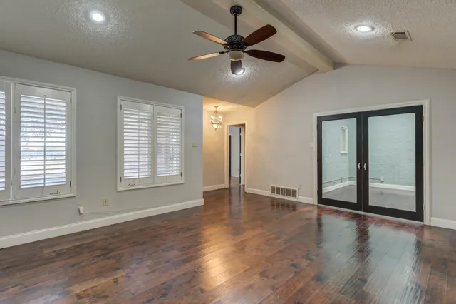 a view of an empty room with window and wooden floor