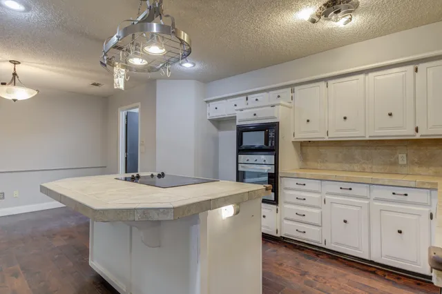 a kitchen with stainless steel appliances granite countertop a sink dishwasher and white cabinets with wooden floor