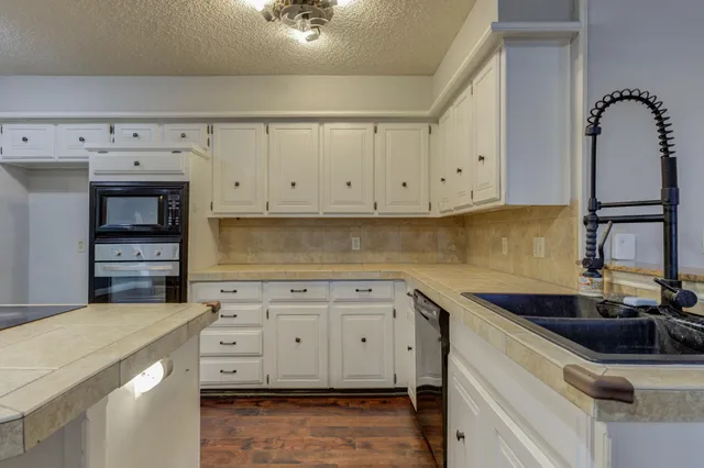 a kitchen with granite countertop white cabinets and sink