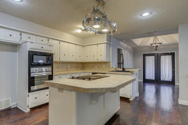 a kitchen with kitchen island a stove a chandelier and a wooden floor