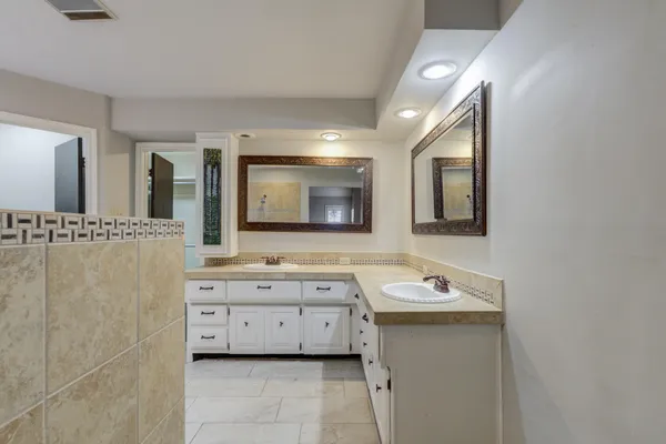 a bathroom with a double vanity sink mirror and bathtub