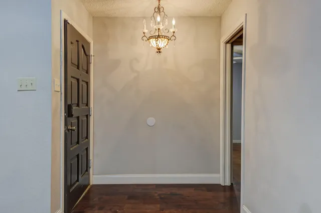 a view of a hallway with wooden floor and chandelier