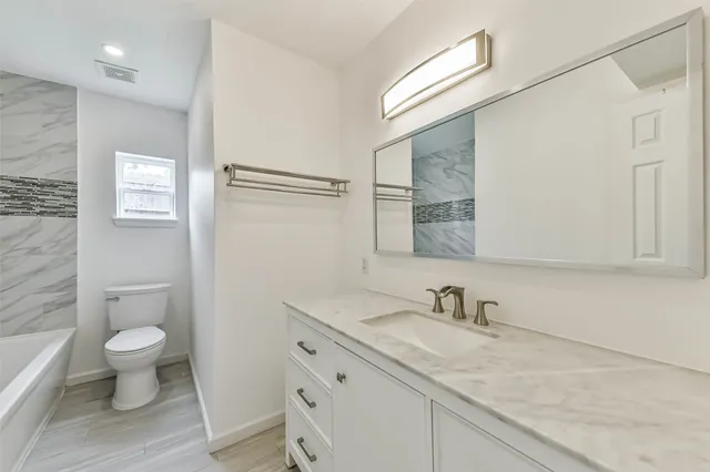 a bathroom with a granite countertop sink a toilet and a mirror