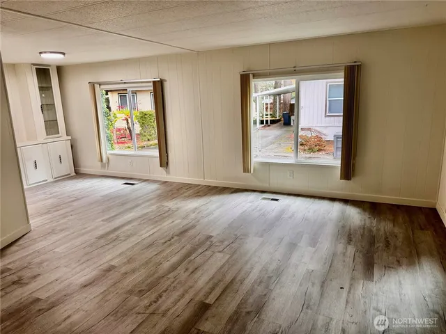 an empty room with wooden floor and windows