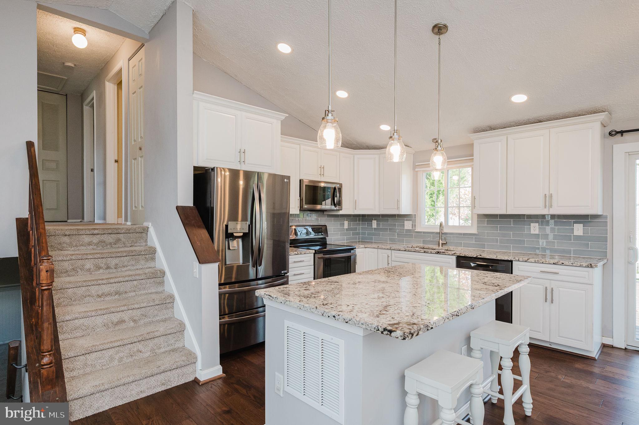 2601 Merrick Way Abingdon, MD 21009 - Photo 10 of 59 a kitchen with kitchen island a refrigerator a stove a sink and white cabinets with wooden floor