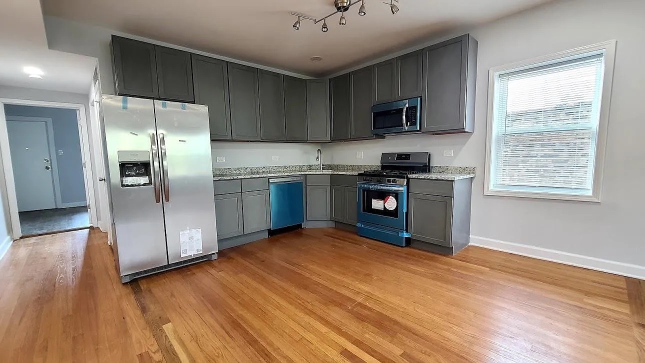 619 East Groveland Park, Unit 2W Chicago, IL 60616 - Photo 15 of 17 a kitchen with stainless steel appliances granite countertop a stove a sink dishwasher a refrigerator and a microwave oven with wooden floor