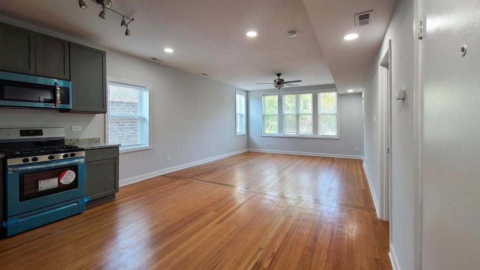 619 East Groveland Park, Unit 2W Chicago, IL 60616 - Photo 5 of 17 a kitchen with stainless steel appliances granite countertop a stove a refrigerator a sink a microwave oven with wooden floor and cabinets