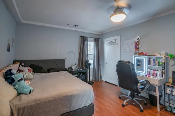 a bedroom with a bed a desk and chair with wooden floor