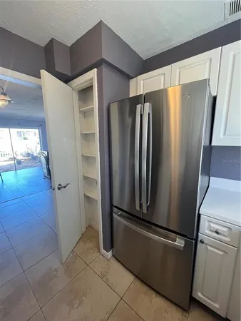 a view of a refrigerator in kitchen and an empty room in wooden floor