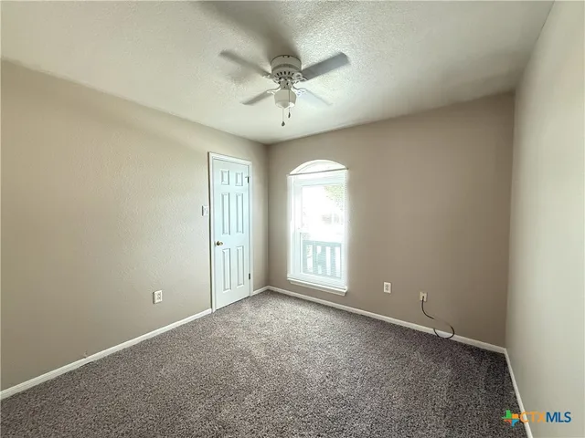 an empty room with a ceiling fan and window