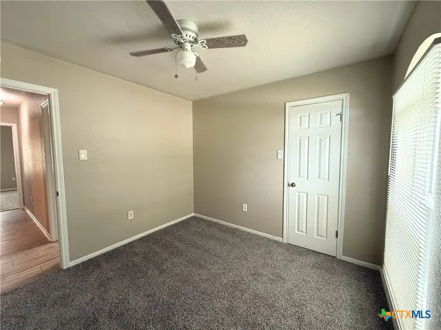 an empty room with fan and entrance