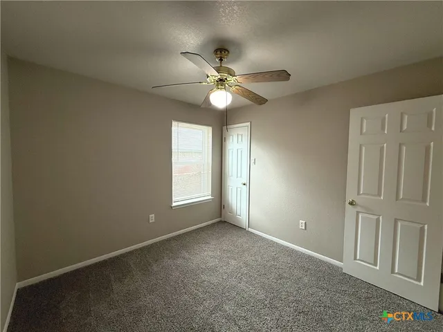 an empty room with windows and fan chandelier fan