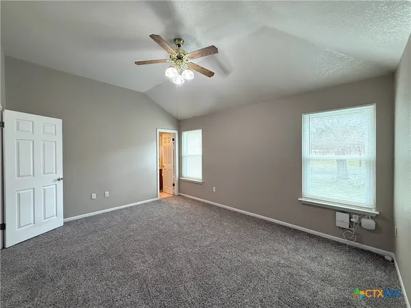 an empty room with windows and fan
