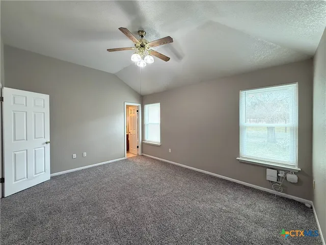 an empty room with windows and fan