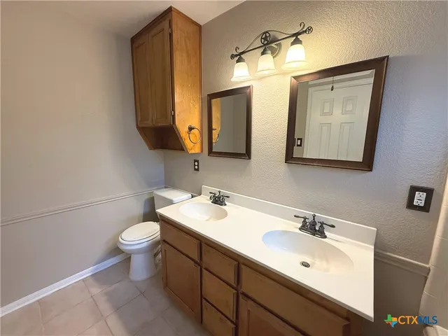 a bathroom with a toilet sink double vanity and mirror