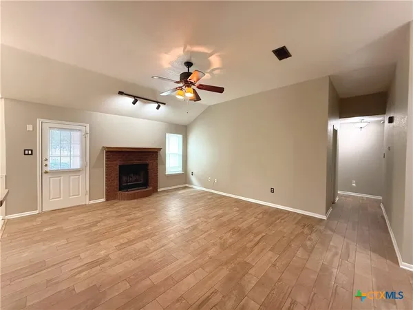 a view of an empty room with a fireplace and a window