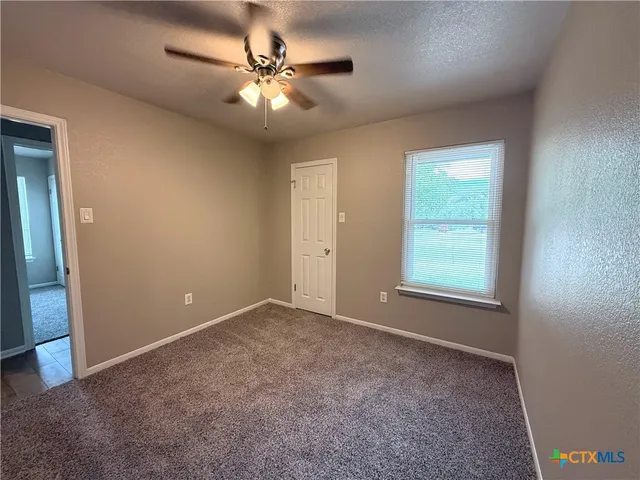 an empty room with windows and fan