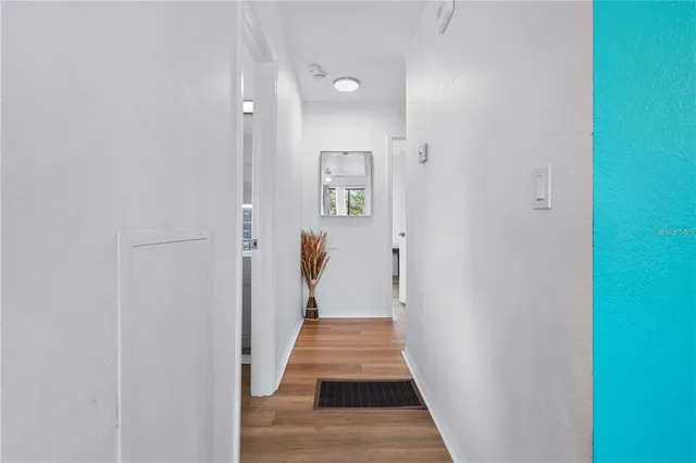 a view of a hallway with wooden floor and a bathroom