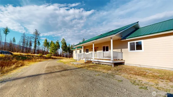 a front view of a house with a yard covered with snow and trees in the background