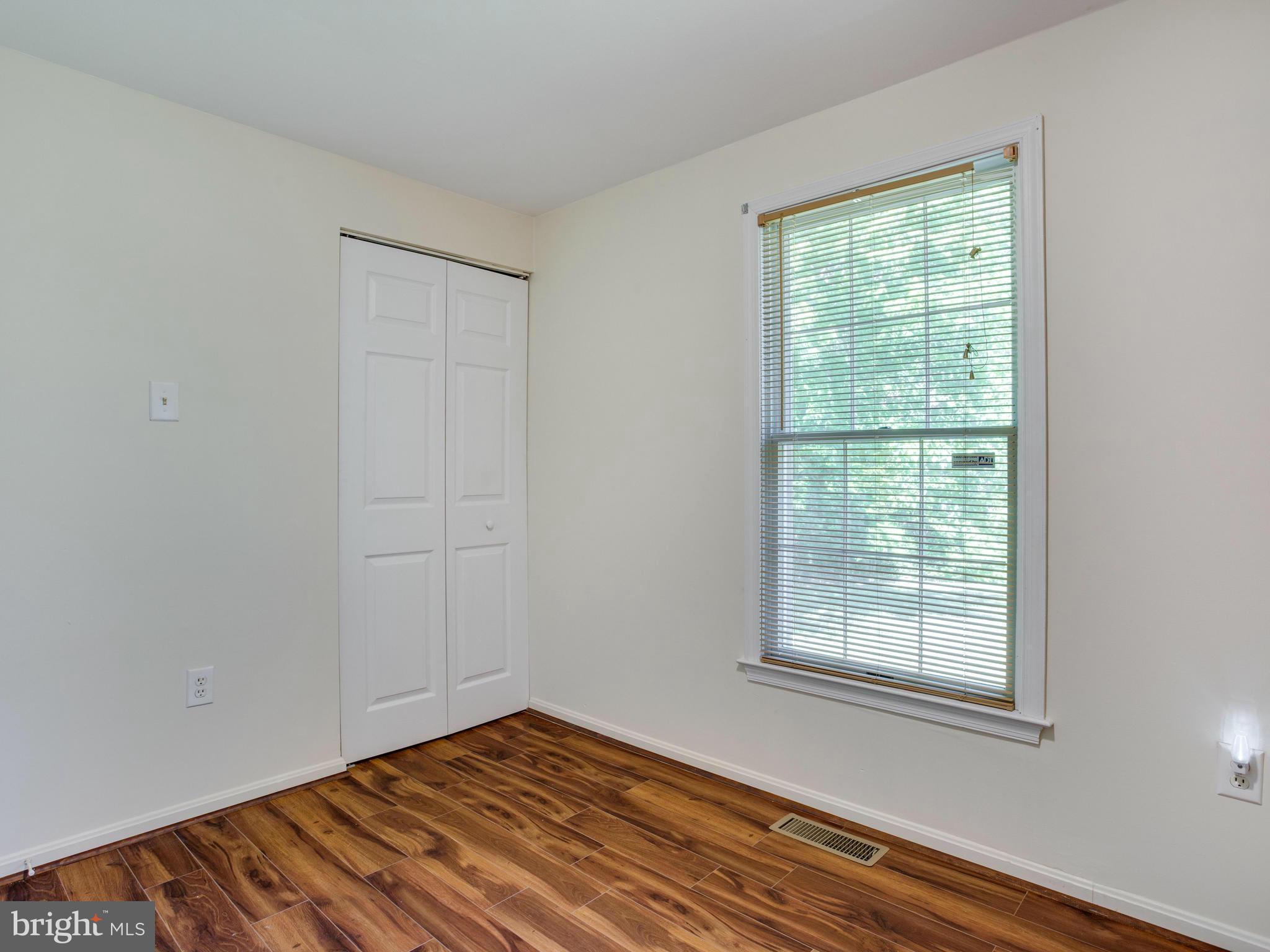 12708 Olivet Road Lusby, MD 20657 - Photo 13 of 22 a view of an empty room with wooden floor and a window